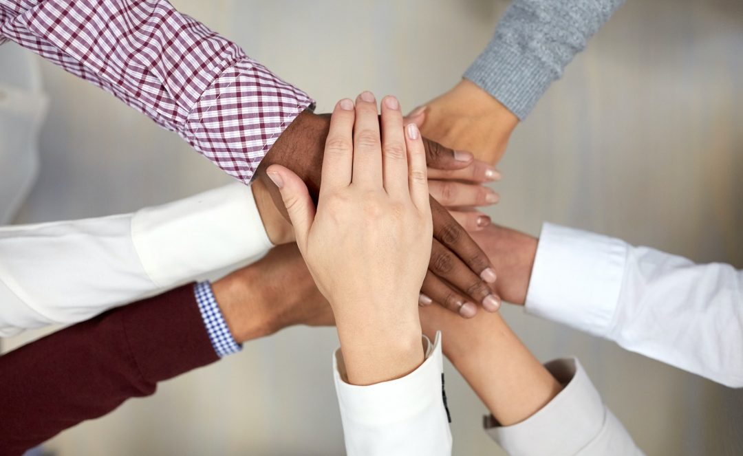 Hands joined in teamwork gesture.